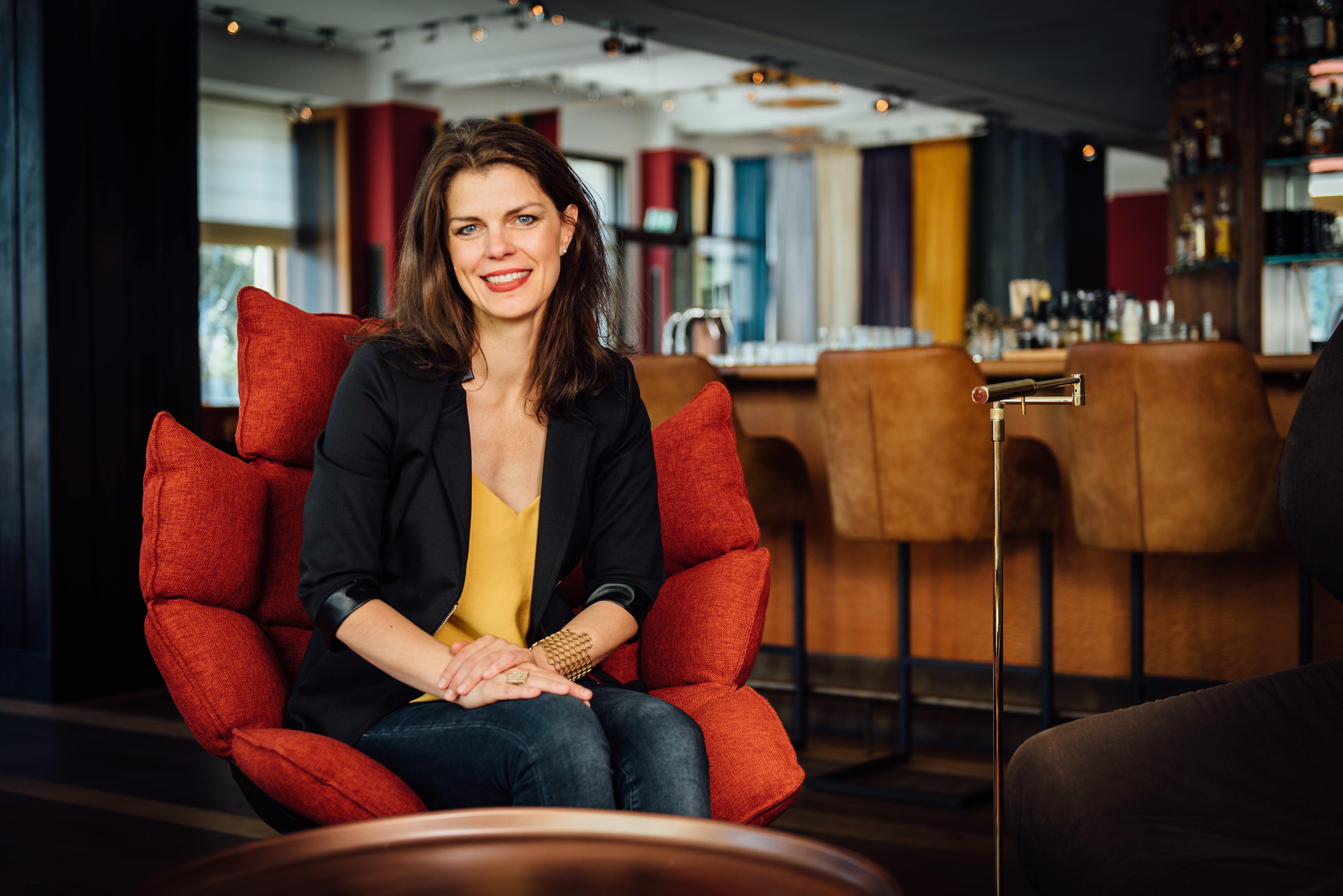 Frau auf einem roten Sessel in einer Hotel-Lobby